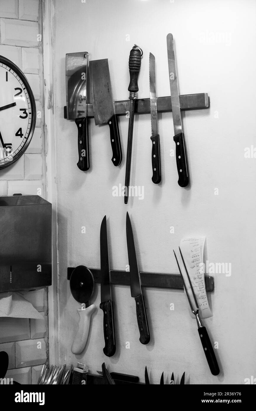 Verschiedene Messer und Küchenutensilien auf magnetischen Gestellen in der Küche Stockfoto