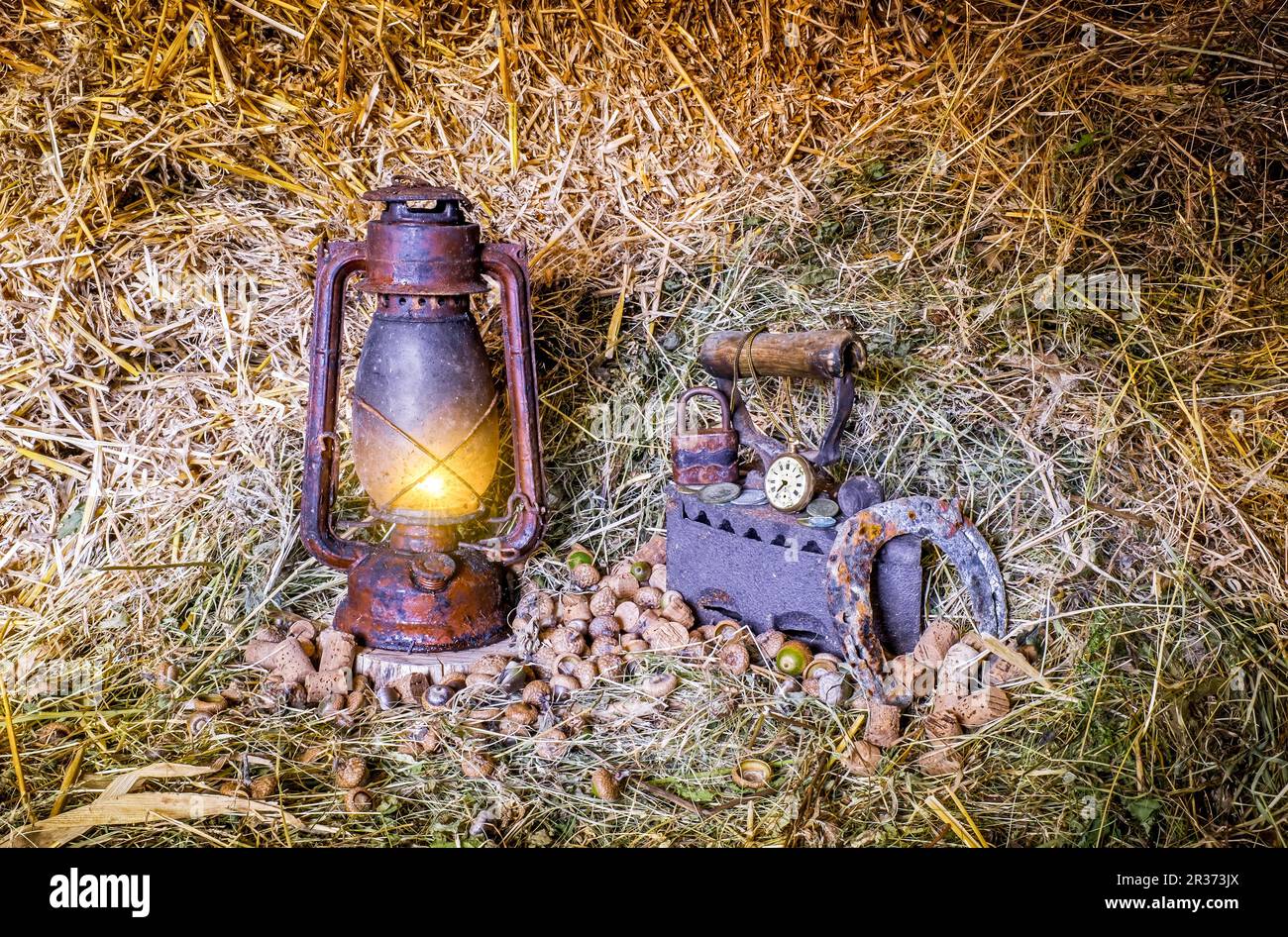 Alte, rot beleuchtete Kerosin-Laterne und alte Dinge im Heu Stockfoto
