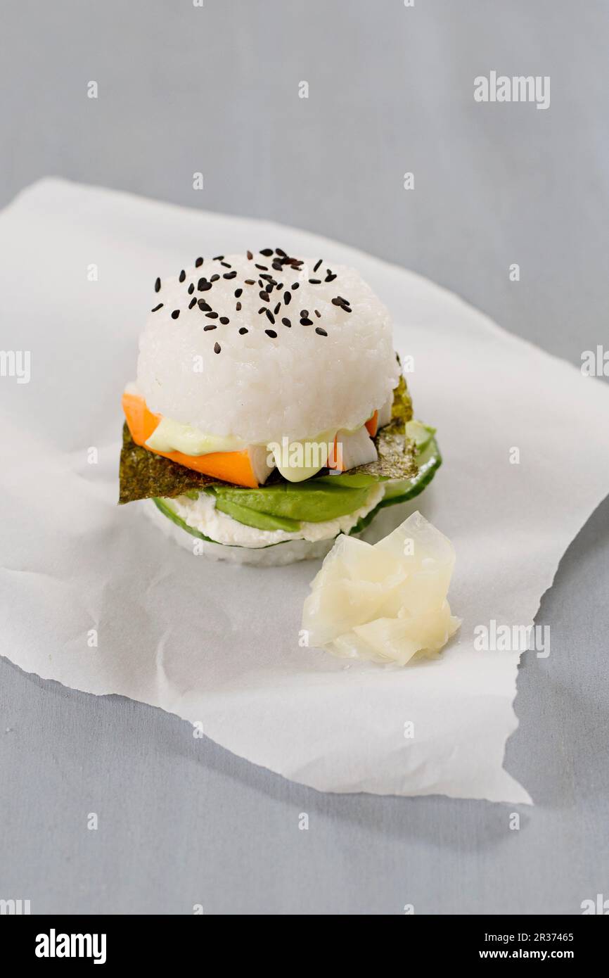 Ein Sushi-Burger mit Gurke, Wasabi Mayo, Surimi, Avocado, Nori und eingelegtem Ingwer Stockfoto