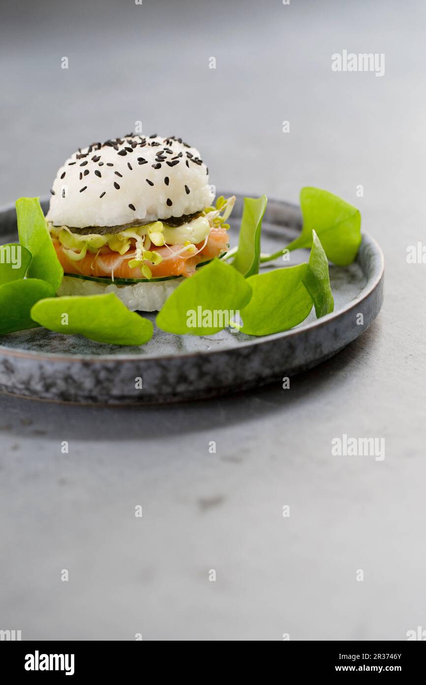 Ein Sushi-Burger mit frischem Lachs, Gurken, noris, Rosenkohl, Wasabi-Mayonnaise und Portulak Stockfoto