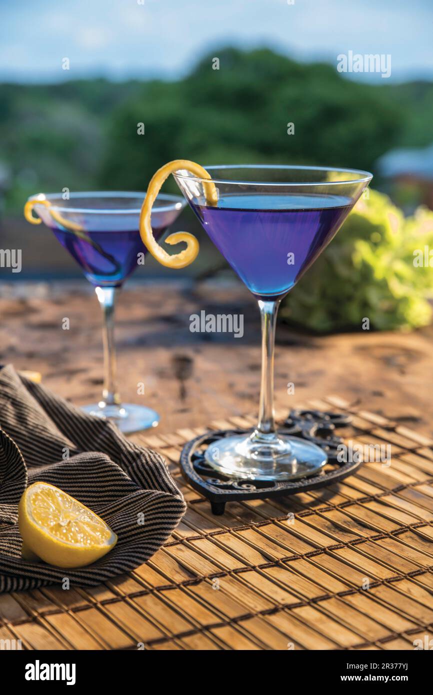 Cocktail in Zitrusblau im Freien in Martinigläsern mit gewellter Zitronenrinde Stockfoto