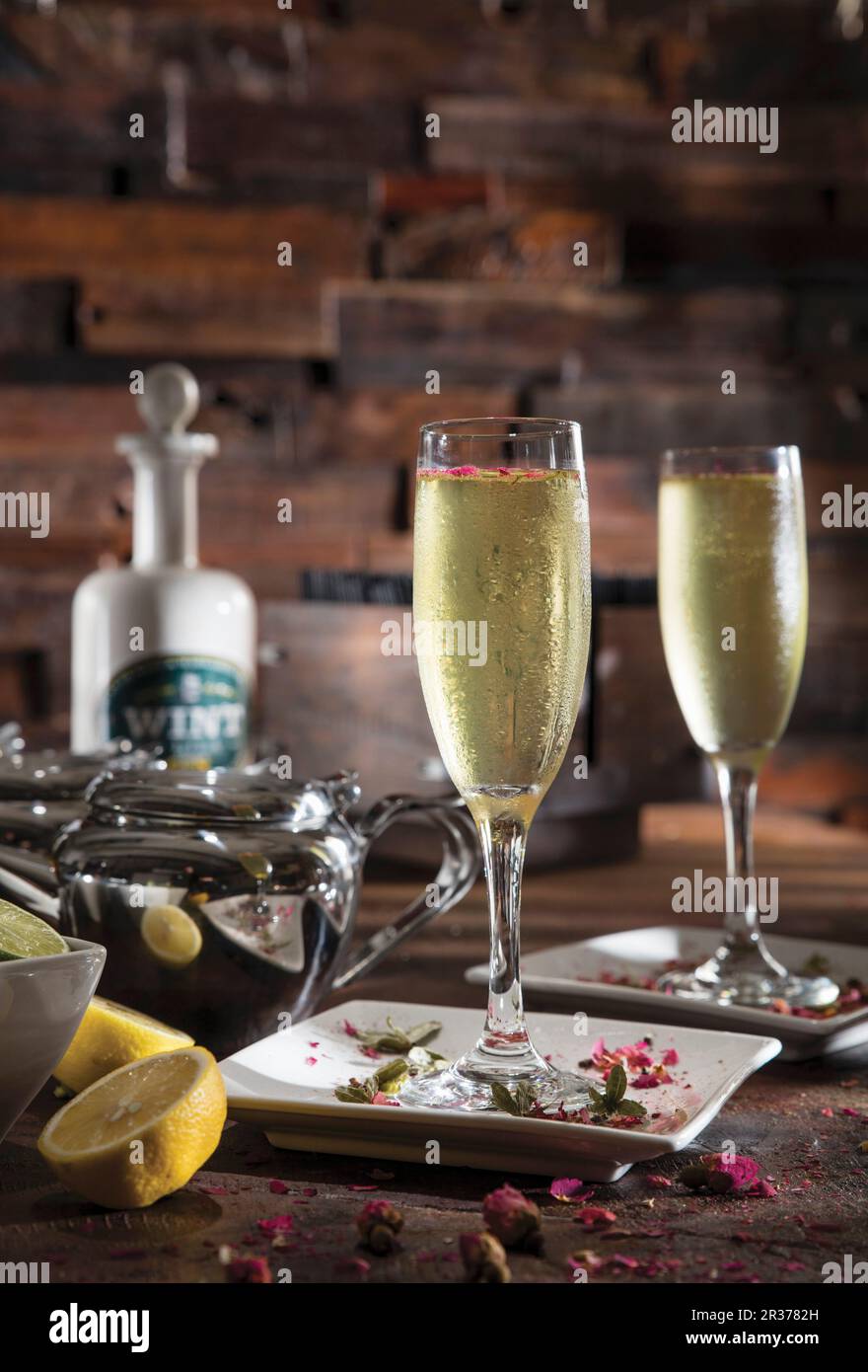 Gin Honig Safran Rosencocktail in Champagnerflöte garniert mit essbaren Rosenblütenblättern Stockfoto