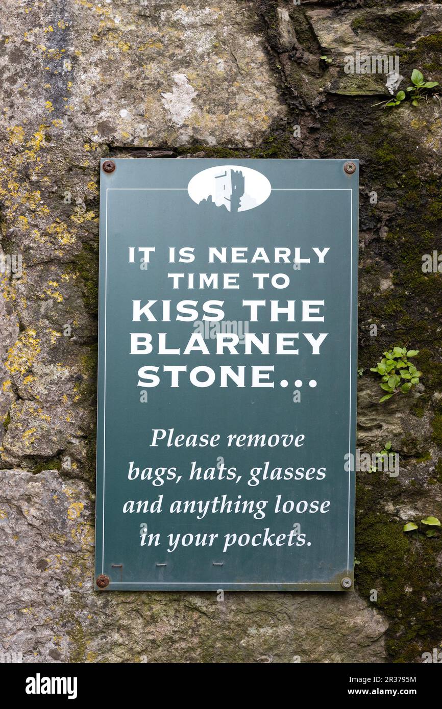 Ein Schild, das die Leute anweist, Hüte, Gläser und Dinge aus den Taschen zu nehmen, während sie sich darauf vorbereiten, den Blarney-Stein im Blarney Castle in Irland zu küssen. Stockfoto