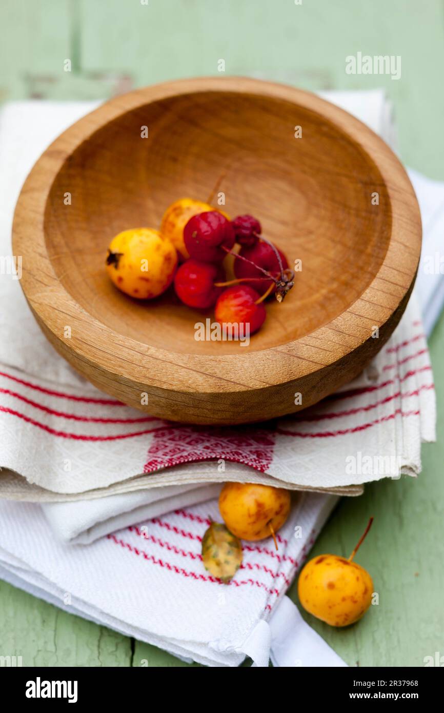 Dekorierte Äpfel in einer Holzschüssel auf Küchentuch Stockfoto