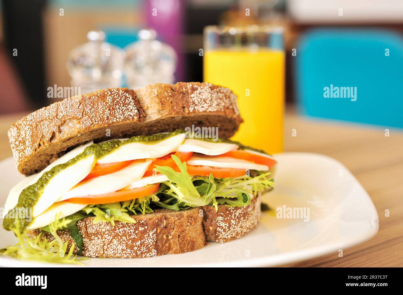 Ein Sandwich mit Mozzarella, Tomaten und Pesto und ein Glas Orangensaft Stockfoto
