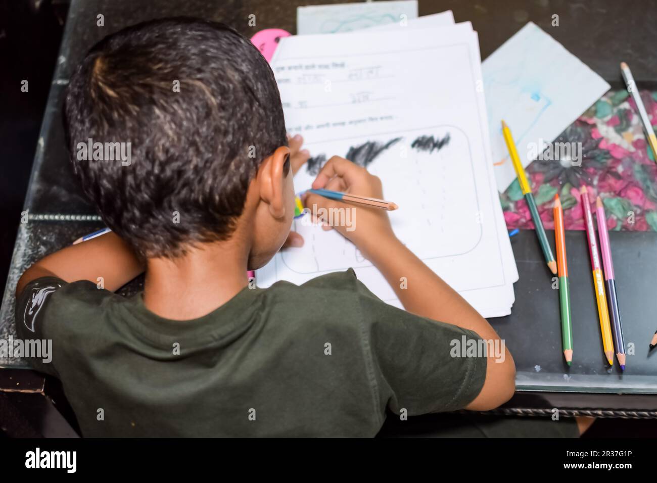 Cleverer indischer kleiner Junge mit bunten Bleistiften Set in verschiedenen Farben während der Sommerferien, süßes indisches Kind Sketching farbenfrohe Zeichnung Stockfoto