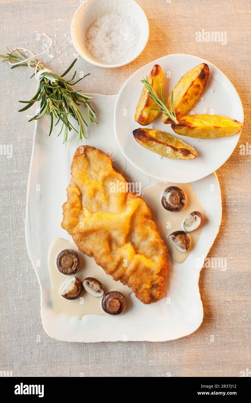 Schnitzel in Weißwein und Pilzsauce mit Kartoffelecken Stockfoto