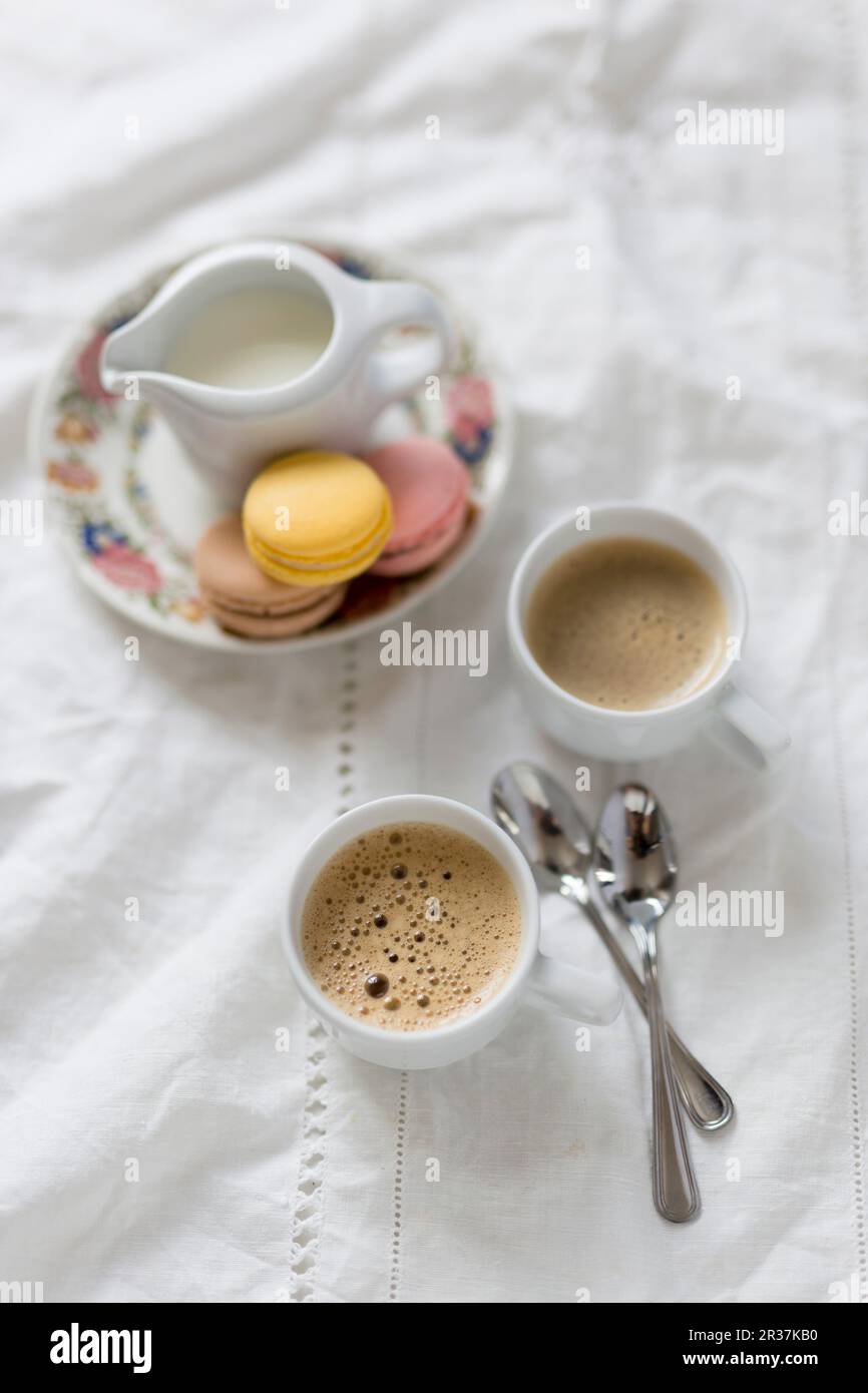 Zwei Tassen Kaffee mit einem Milchkännchen und Makronen Stockfoto