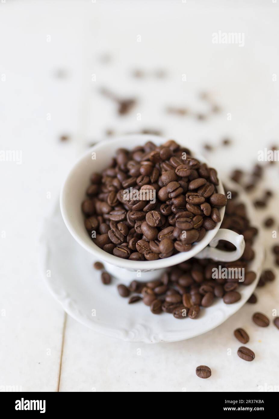Kaffeebohnen in einer Kaffeetasse und auf einer Untertasse Stockfoto