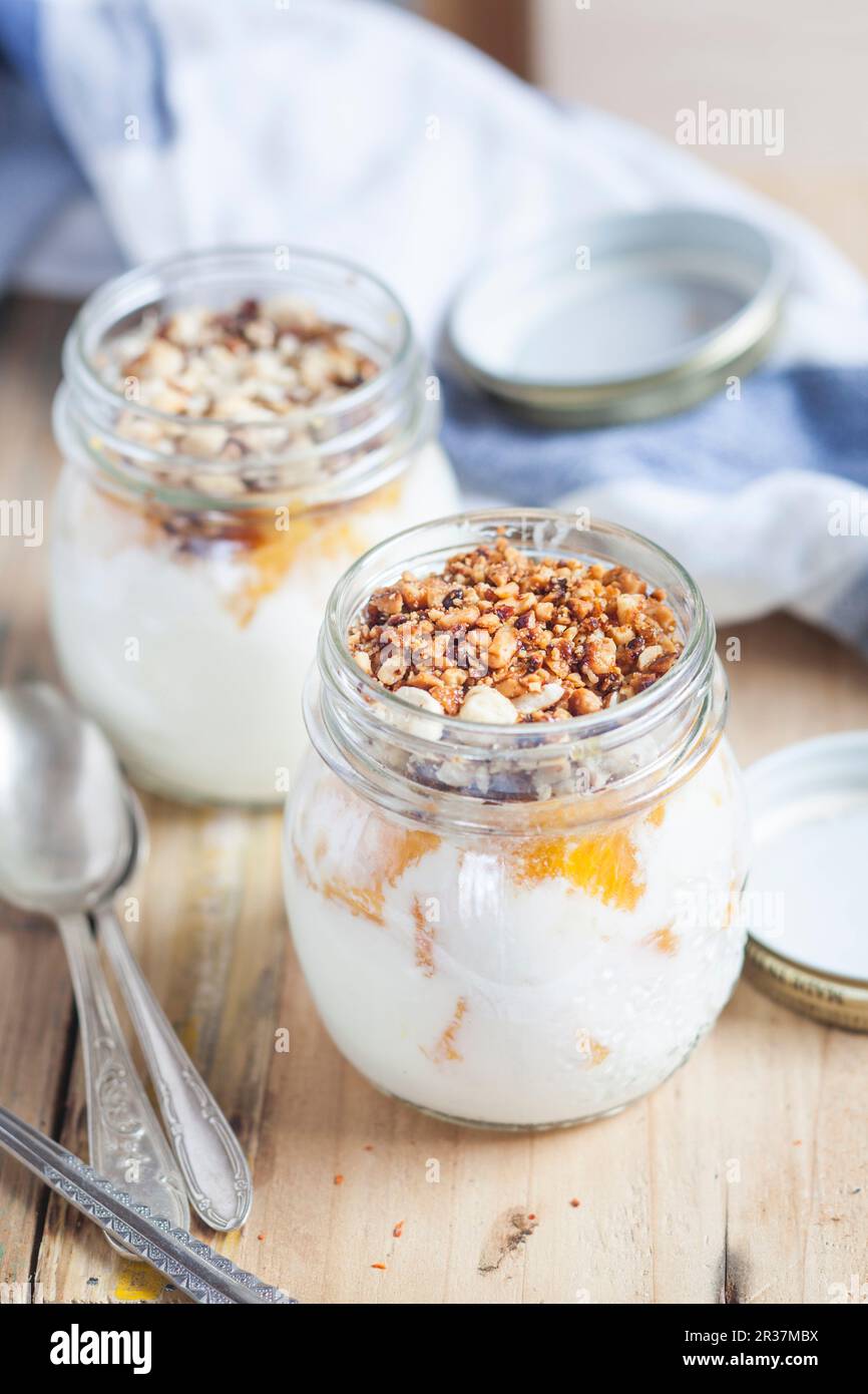 Joghurt mit Orangen Stückchen und gehackten Nüssen Stockfoto