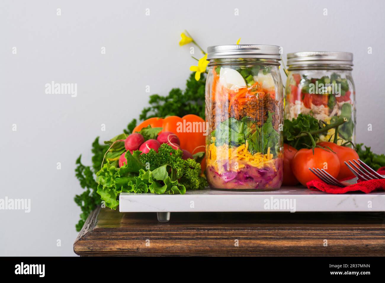 Zwei 2-in-1-Salate, die in Gläsern mit Spinat, Bohnen, Käse und Eier Stockfoto