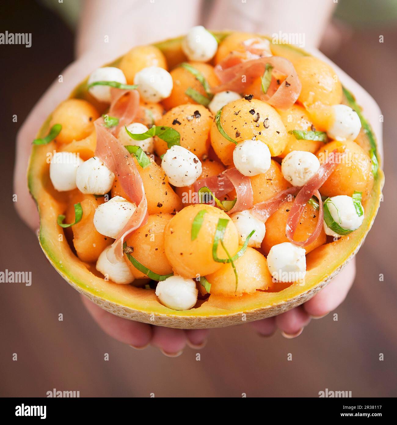 Melonensalat mit Mozzarella und Proscuitto in einer ausgehöhlten Melone Stockfoto