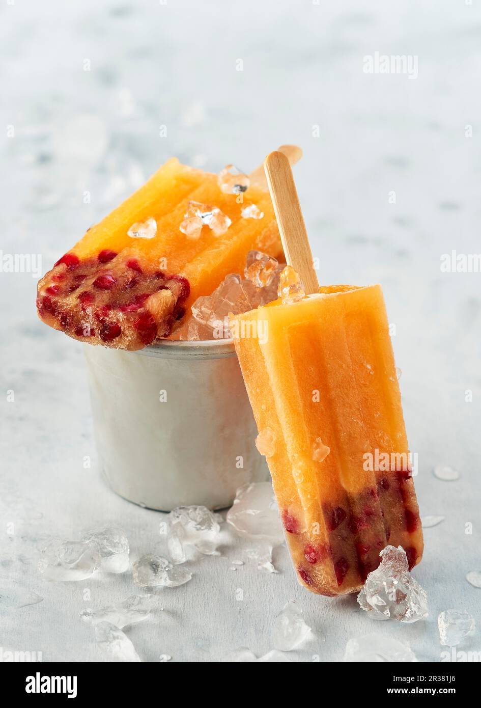 Mango- und Granatapfeleis Lollies auf Stöcken mit zerstoßenem Eis Stockfoto