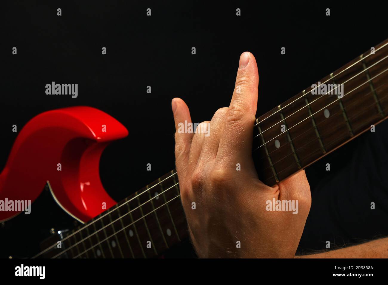 Hand mit roten Gitarre und Teufel Hörner isoliert auf Schwarz Stockfoto Hand mit roten Gitarre und Teufel Hörner isoliert auf Schwarz Stockfoto