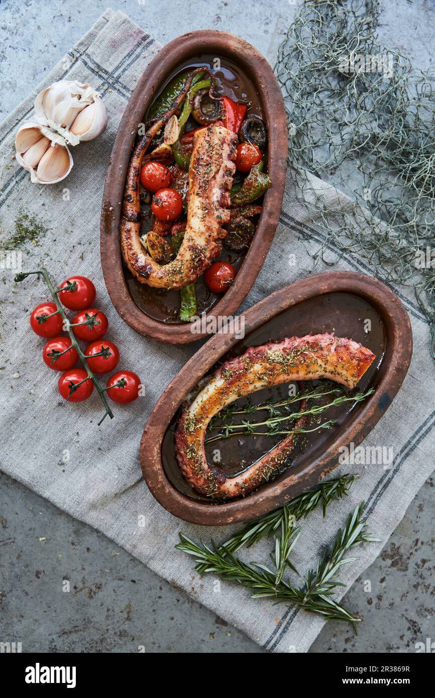 Tintenfisch-Tentakel mit Tomaten, Paprika und Kräutern in rustikalen Serviergerichten Stockfoto