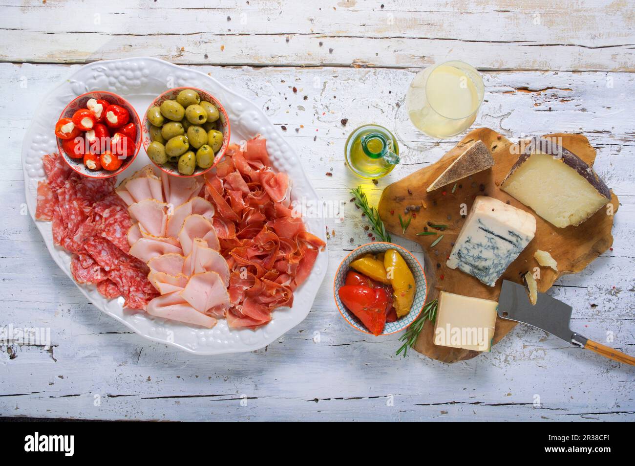 Käse- und Wurstplatte mit Oliven, gefülltem Gemüse und Weißwein Stockfoto