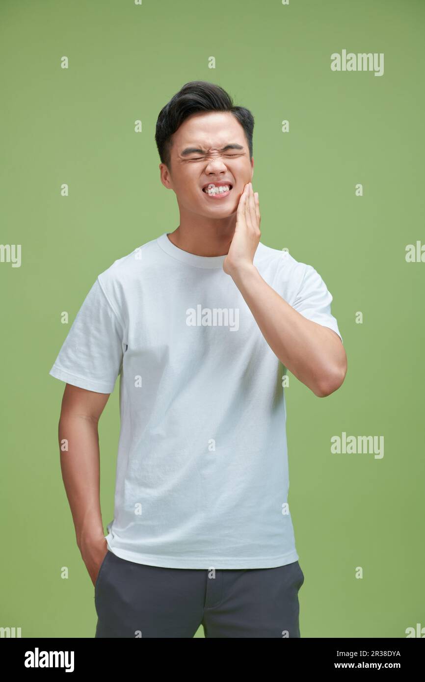Ein Mann fühlt Zahnschmerzen mit grünem Hintergrund, asiatisch Stockfoto
