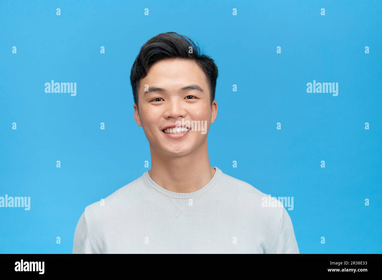 Porträt von einem gutaussehenden jungen Mann vor blauem Hintergrund lächelnd Stockfoto