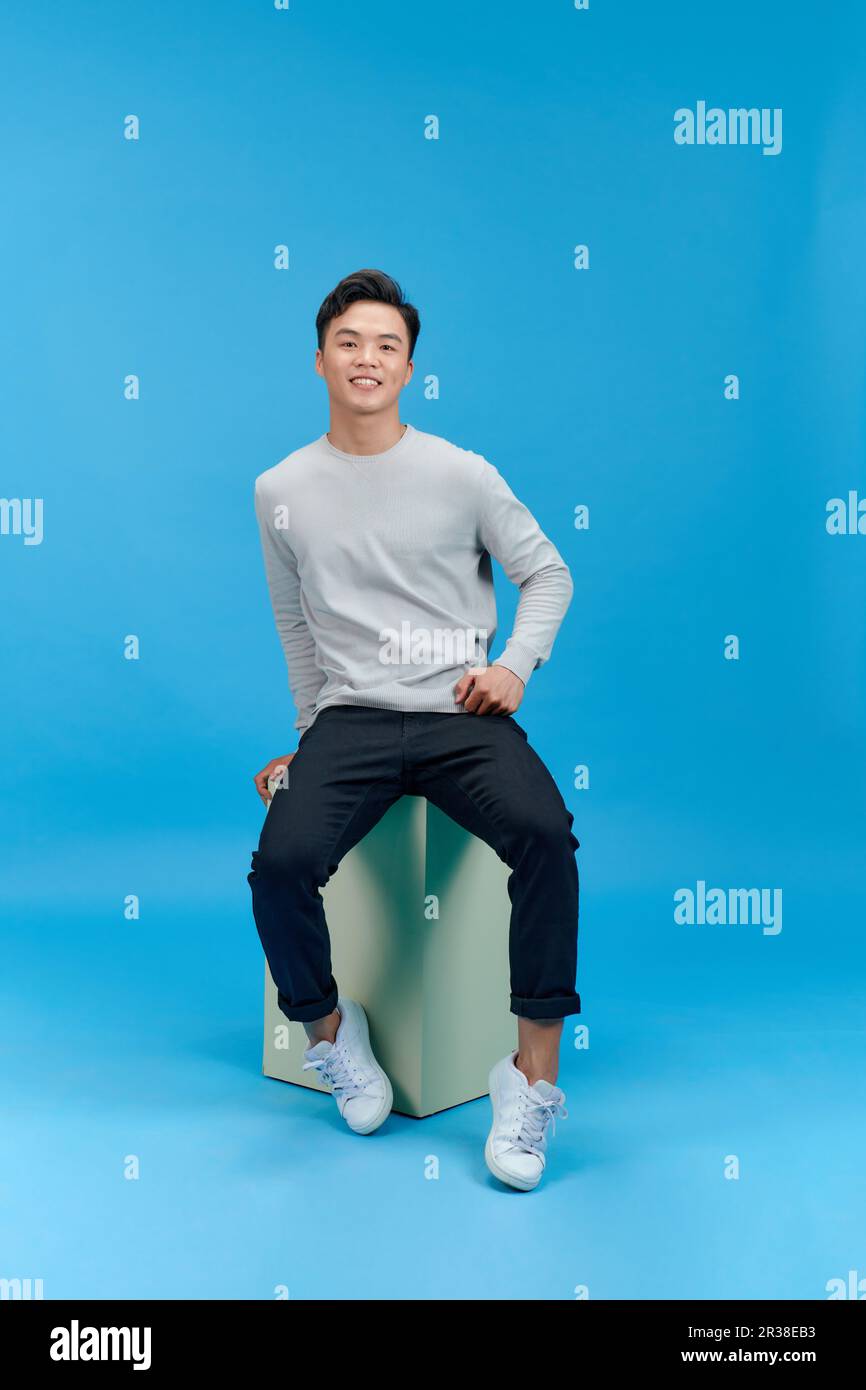 Junger Asiate, der auf der Säule sitzt, isoliert auf weiß. Stockfoto