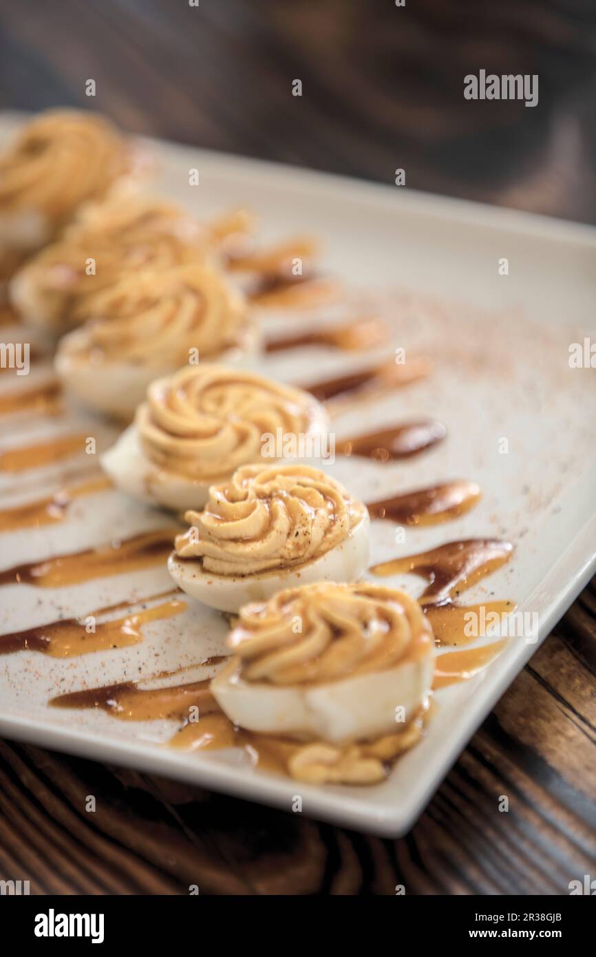 Deviled Eggs (gefüllte Eier) diagonal auf einem weißen Teller angeordnet Stockfoto