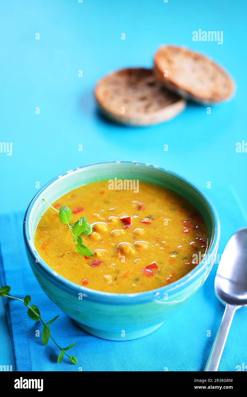 In einer rustikalen Schüssel mit gegrilltem Brot im Hintergrund eine urige Suppe Stockfoto