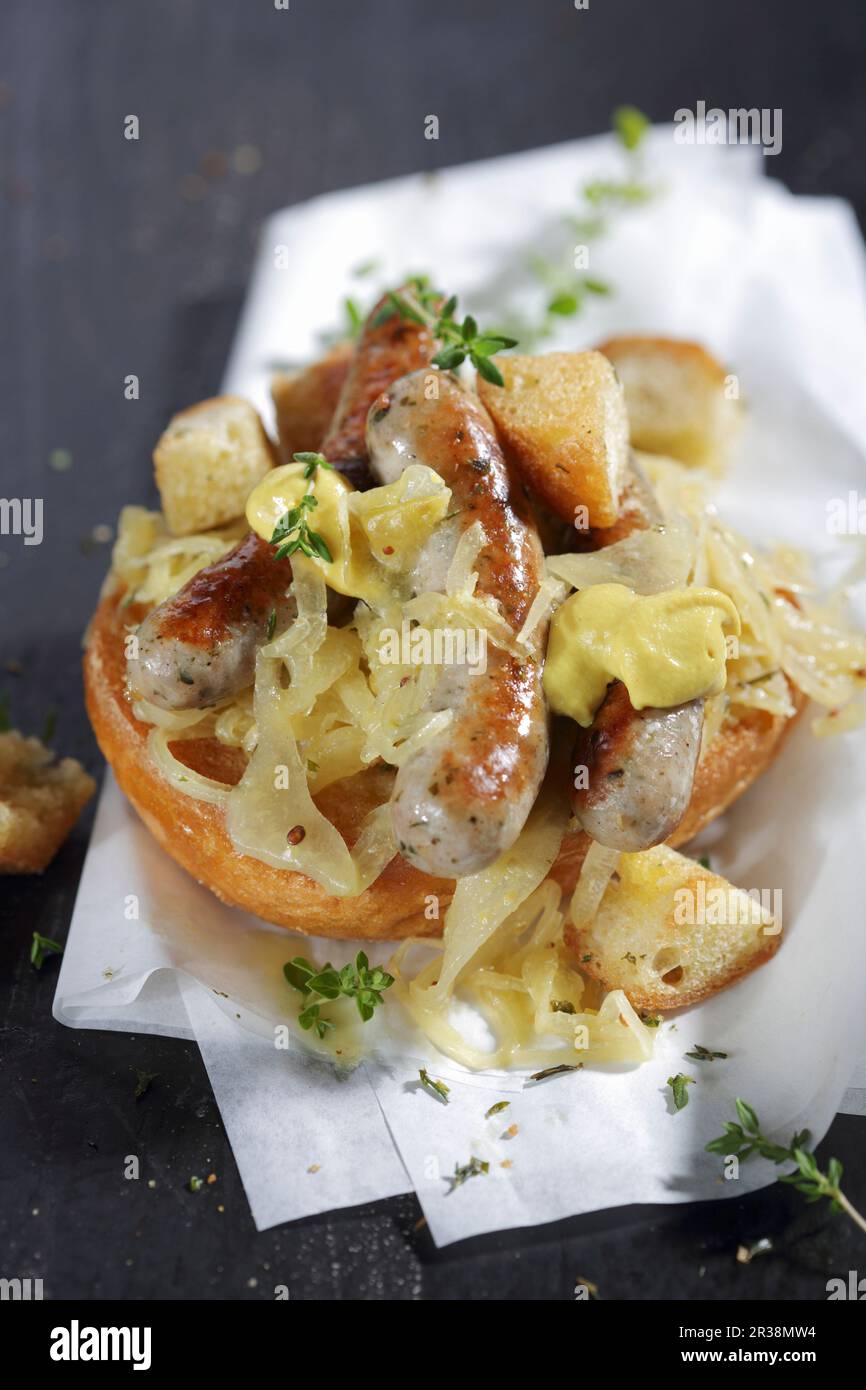 Nürnberger Würstchen mit Senf und Sauerkraut auf einem Brötchen Stockfoto