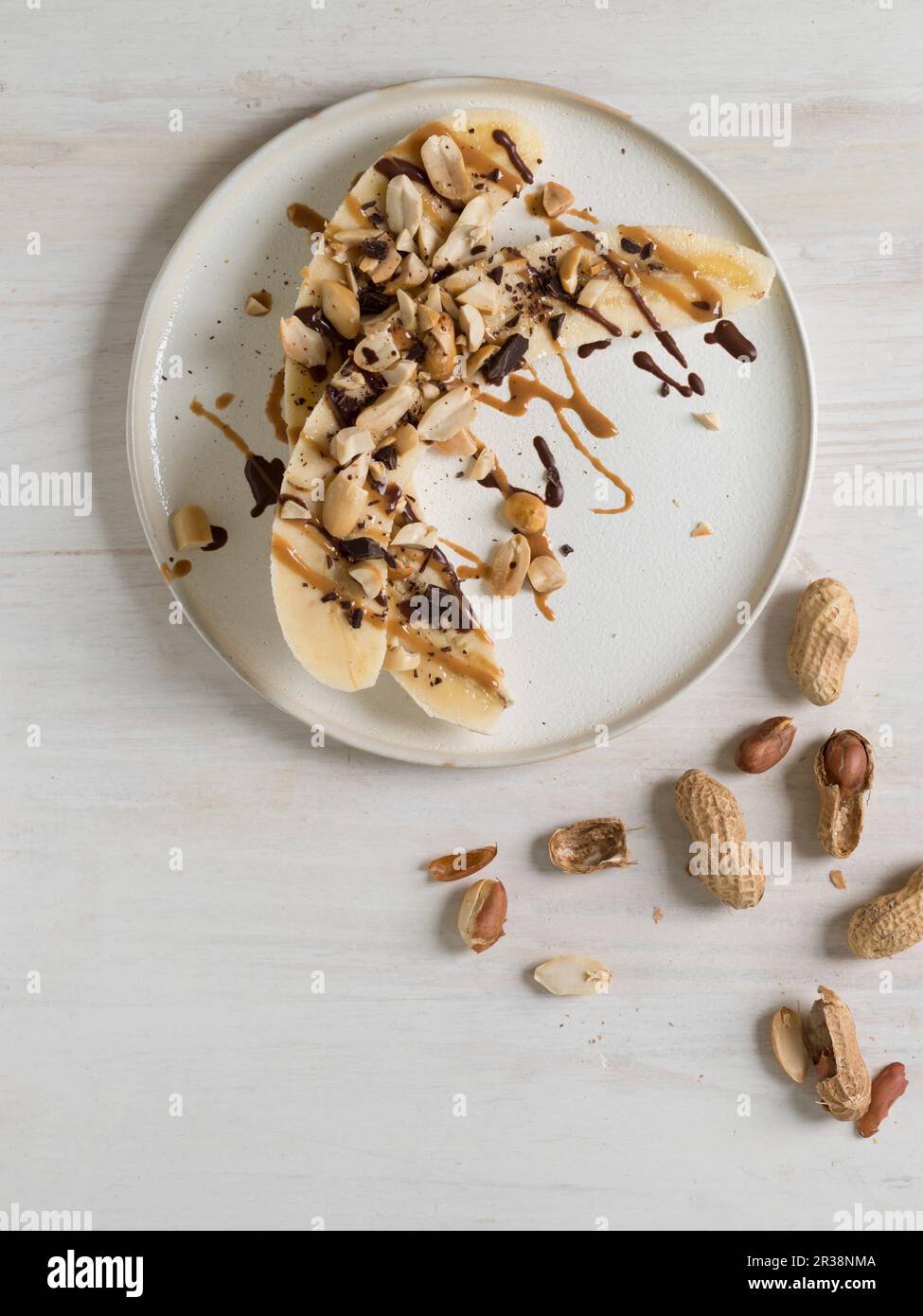 Halbierte Bananen mit Erdnüssen, Erdnussbutter und Schokolade Stockfoto