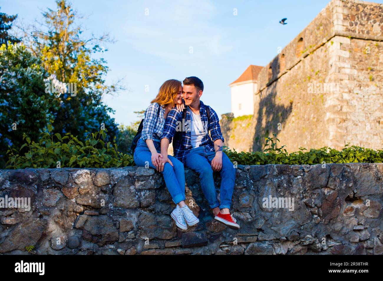 Romantisches Paar sitzt auf einer Wand in der Nähe der Burg Stockfoto