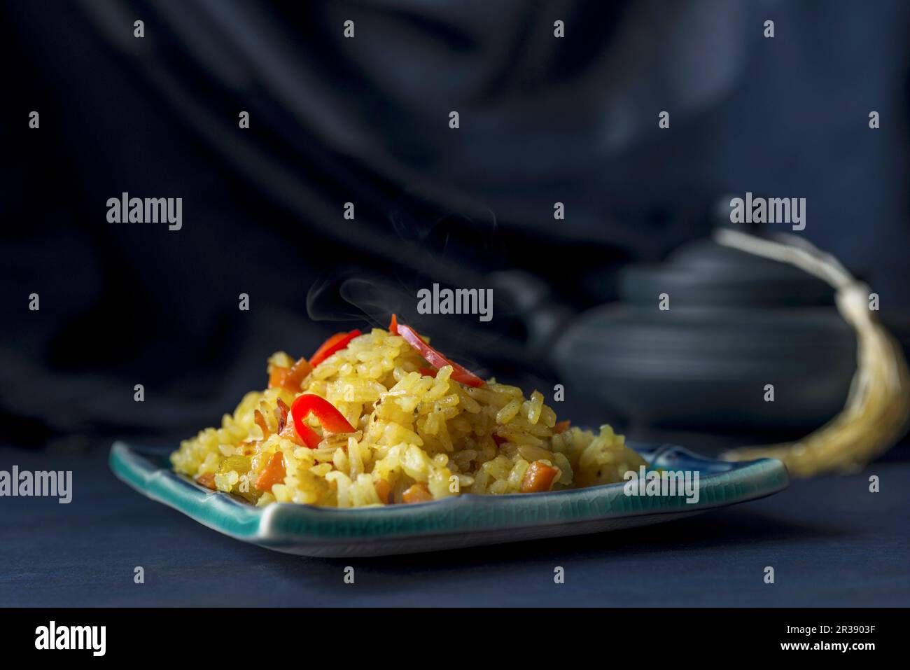 Fleischfreier Pilaf garniert mit roter Chili-Paprika auf dunkelblauem Hintergrund Stockfoto