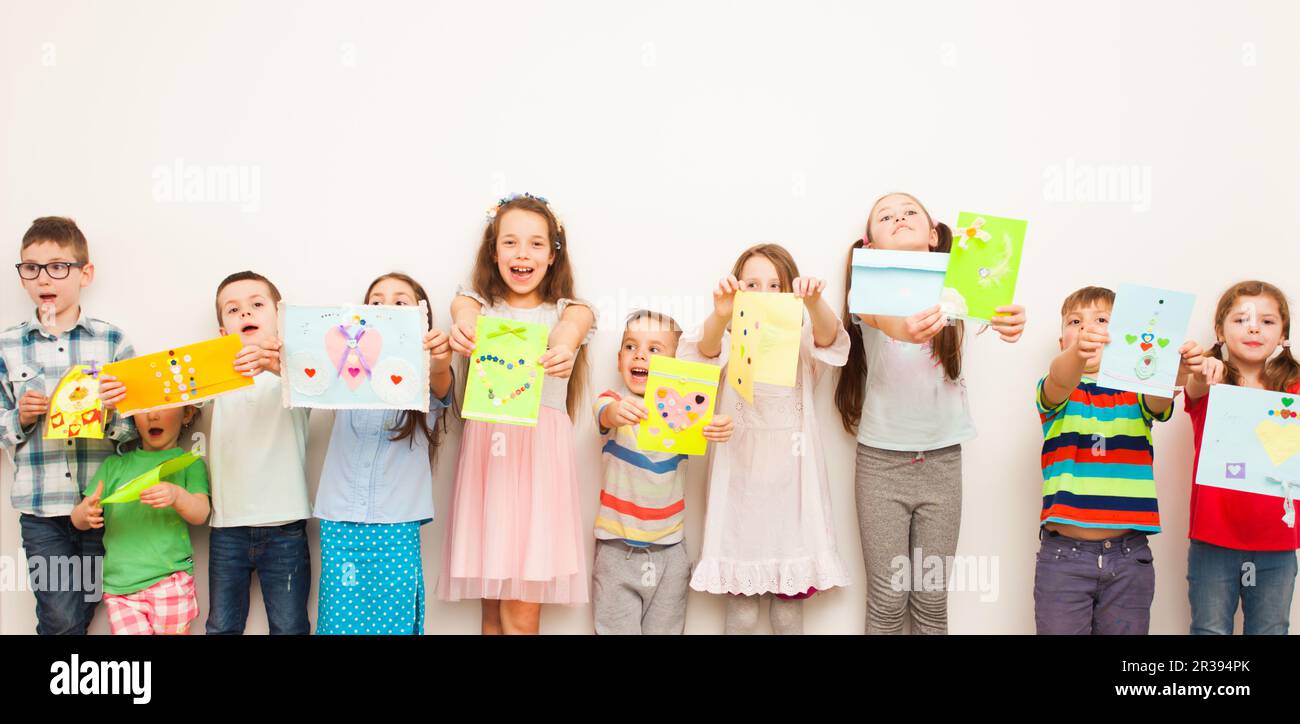 Kinder stehen hintereinander und halten selbstgefällige Grußkarten, Heimwerkerkonzept Stockfoto
