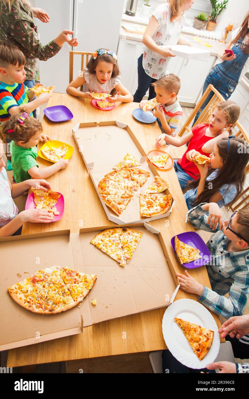 Kinder essen Pizza zu Hause, Kinderparty Stockfoto