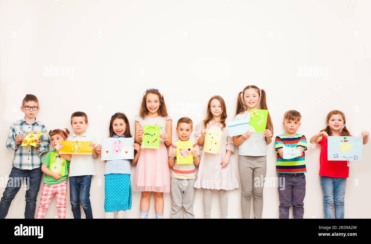 Happy Kids zeigen Ihre Grußkarte über weiße Wand. Handgeschöpftes Papier Handwerk für Kinder Stockfoto