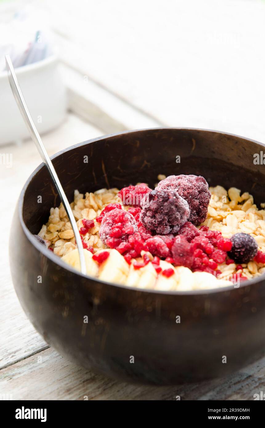 Eine Smoothie-Schüssel mit Müsli, Banane und gefrorenen roten Früchten Stockfoto