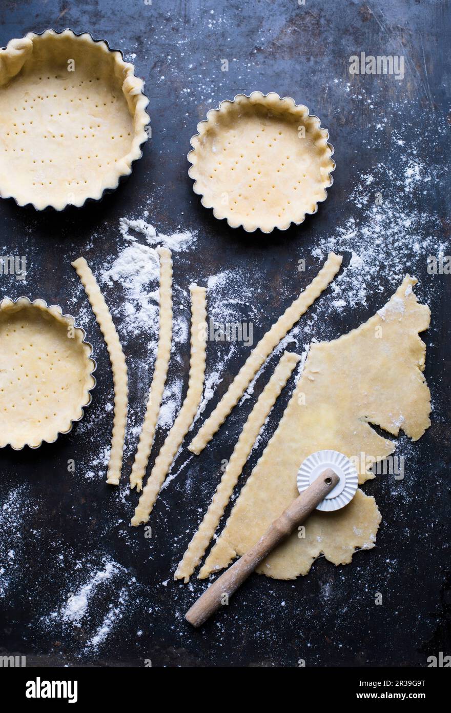 Kuchengebäck in Etuis, auf einer bemehlten Oberfläche gerollt und in Streifen geschnitten Stockfoto