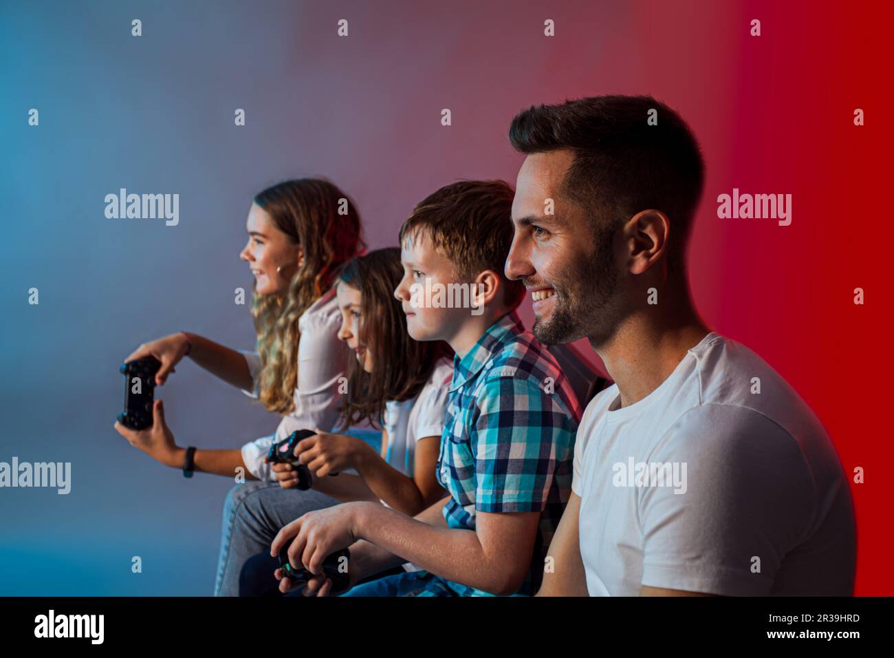 Vater, Mutter und Kinder spielen ein Videospiel in einem modernen Spielclub Stockfoto