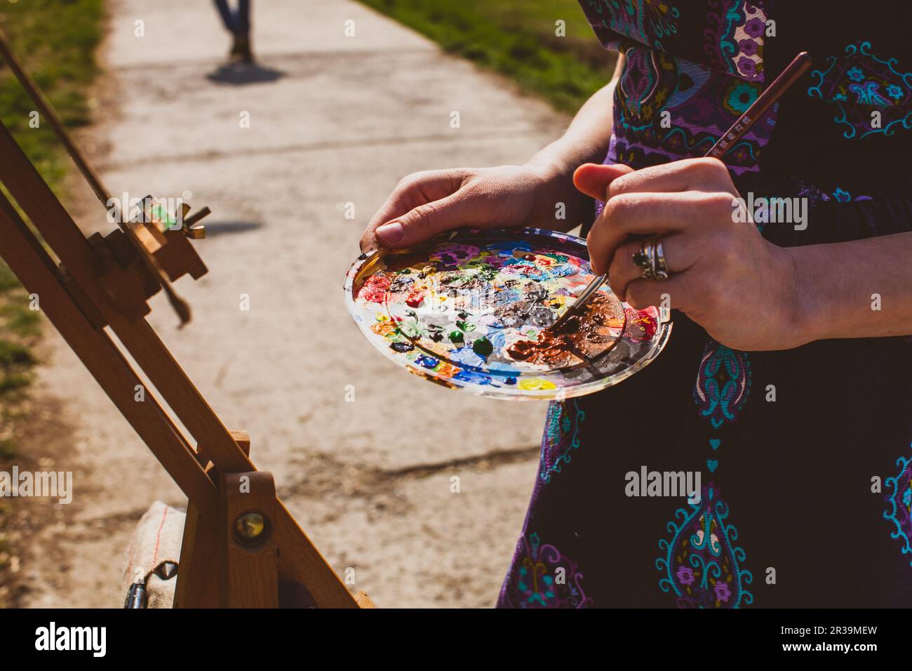 Künstler mischen Acrylpanits auf Palette. Mädchen malt ein Bild im Freien. Stockfoto