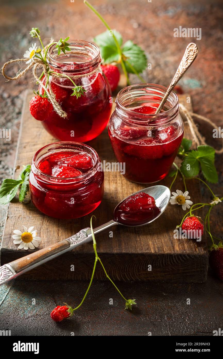 Hausgemachte Erdbeermarmelade in Glasgefäßen auf Holzbrett im rustikalen Stil. Gesundes Frühstück Stockfoto