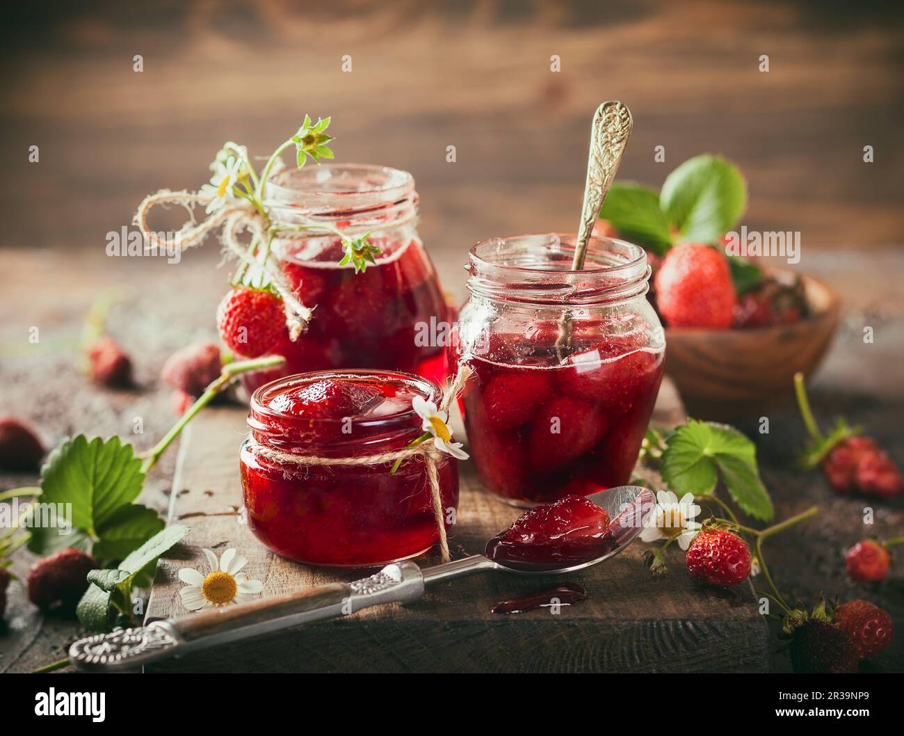 Hausgemachte Erdbeermarmelade in Glasgefäßen auf Holzbrett im rustikalen Stil. Gesundes Frühstück. Bild mit Tonwertkorrektur Stockfoto