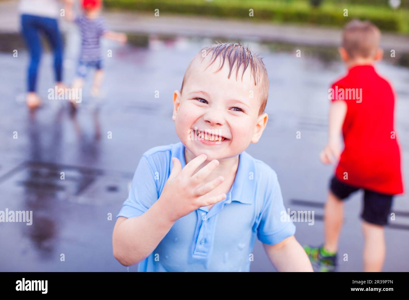 Ein glückliches Kleinkind erfrischt sich in einem Brunnen Stockfoto