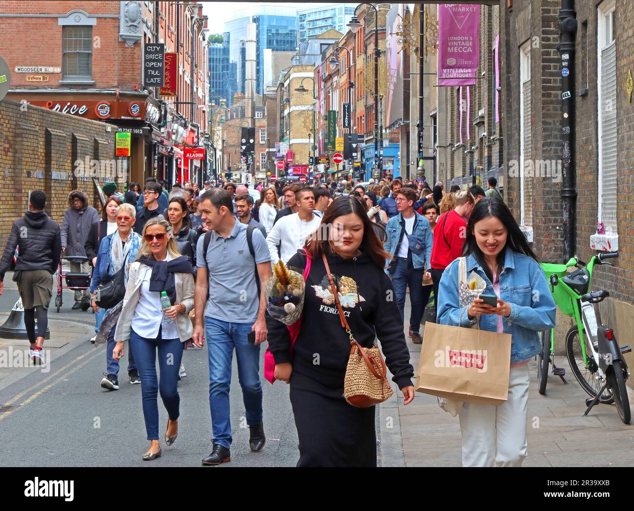 Überfüllte Straße mit Touristen in einer belebten Brick Lane, London, GB, E1 6QL, mit Blick nach Osten in Richtung Moschee und Aldgate East Stockfoto