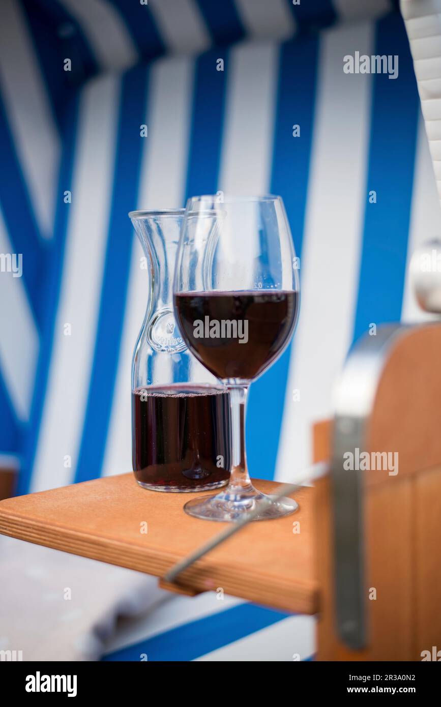 Ein Glas Rotwein und eine Karaffe Wein in einem Liegestuhl Stockfoto
