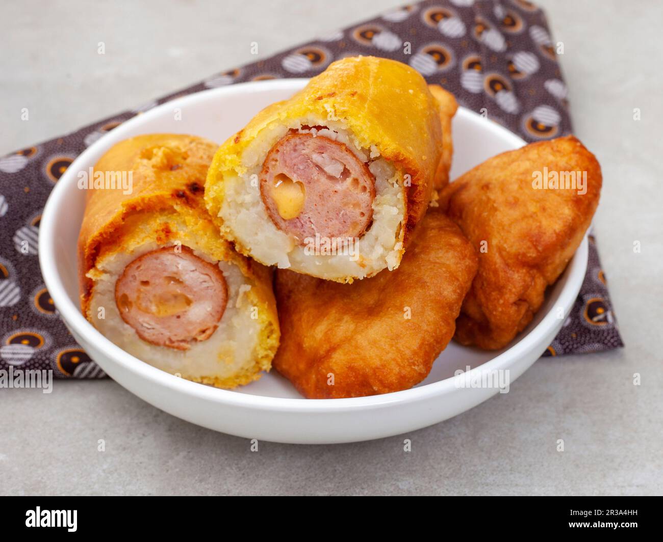 Traditionelle südafrikanische russische Wurst Sputnik oder frittierte Würstchen mit Mash-Überzug und traditionellem bedruckten Stoff Stockfoto