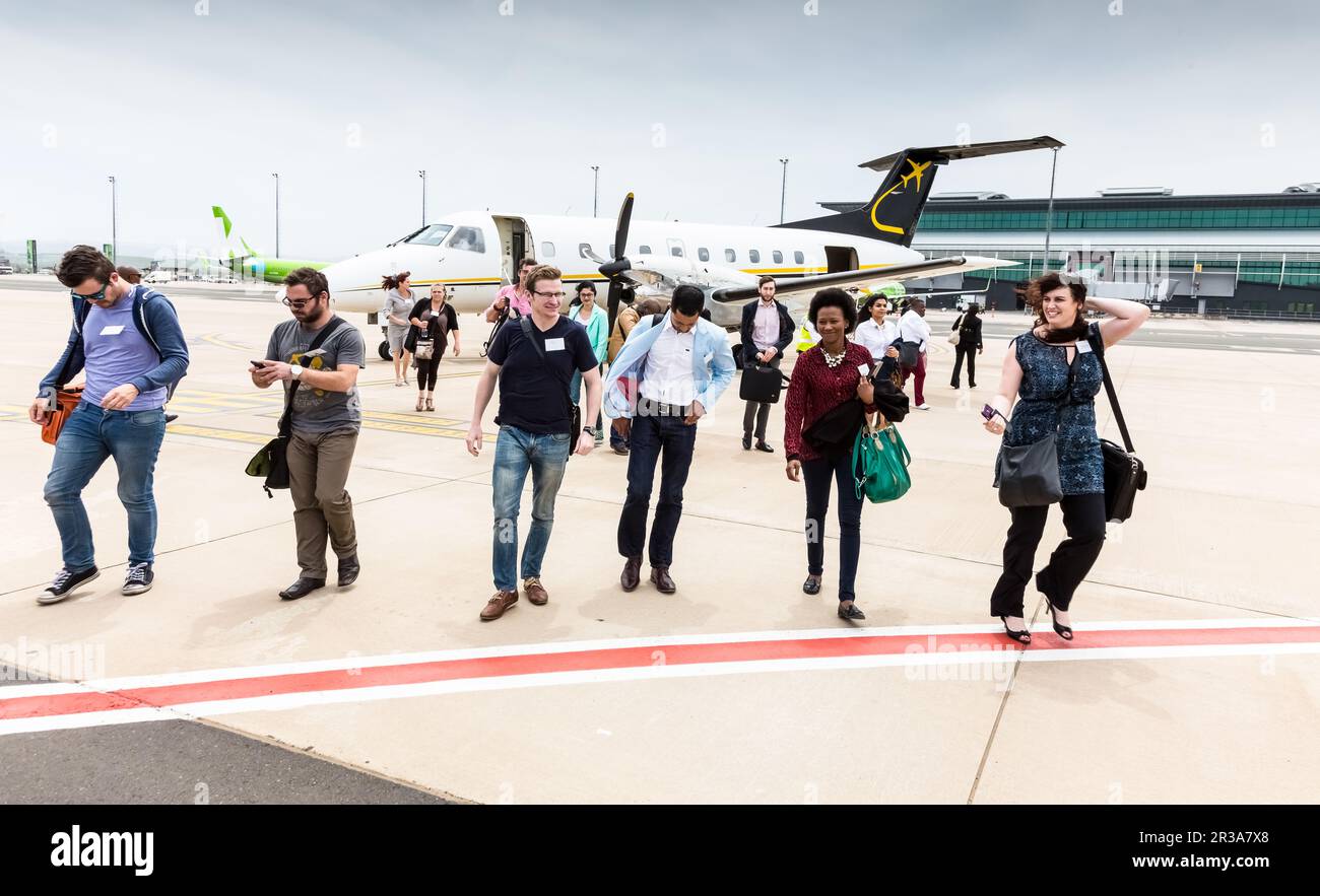 Passagiere, die in einem kleinen Charterflugzeug mit Propellertriebwerk am lokalen Flughafen aussteigen Stockfoto