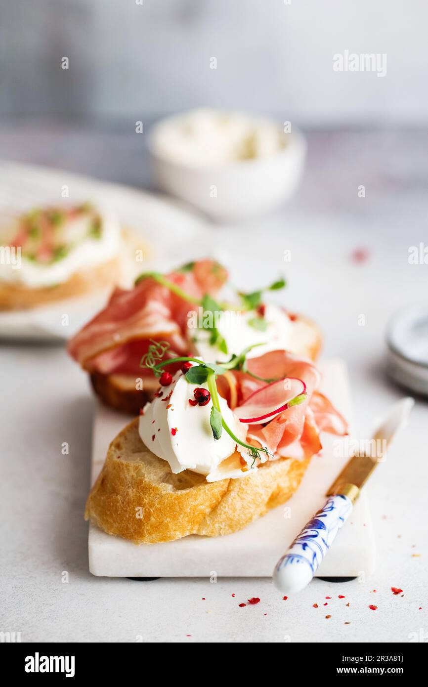 Bruschetta mit Prosciutto und Frischkäse. Brot mit geräuchertem Speck und Frischkäse. Getoastetes Brot Stockfoto