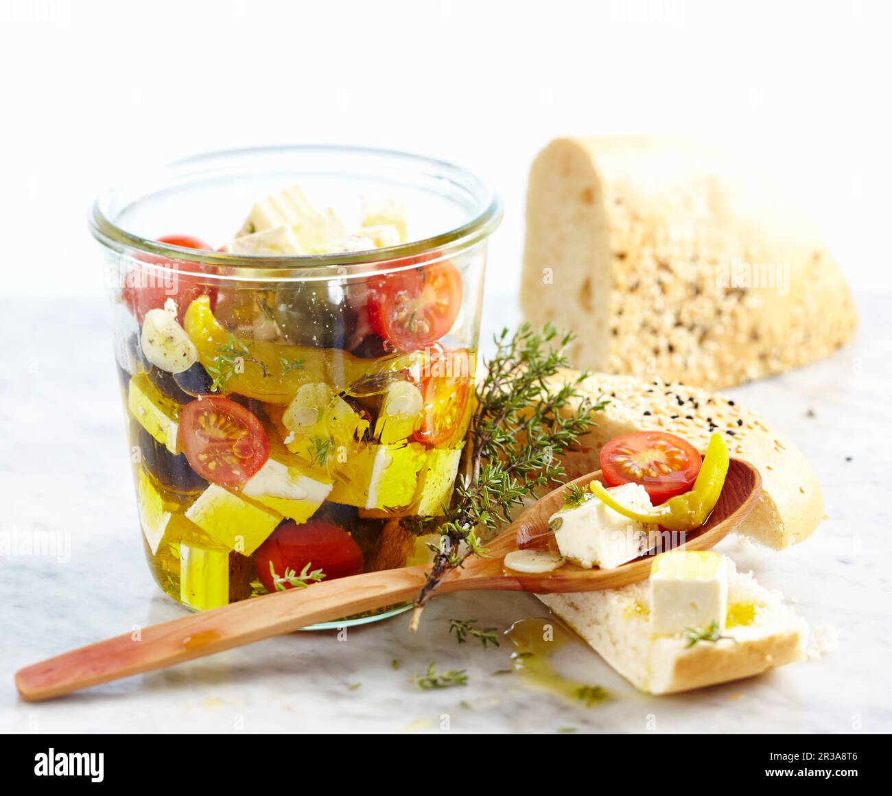 In Olivenöl konservierter Fetakäse mit Tomaten, Knoblauch, Jalapenos und Oliven, serviert mit ungesäuertem Sesambrot Stockfoto