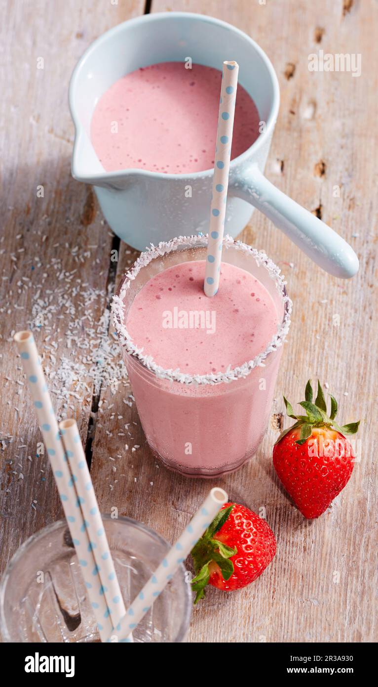 Ein cremiger Erdbeeren- und Kokosnuss-Shake mit einem Strohhalm Stockfoto