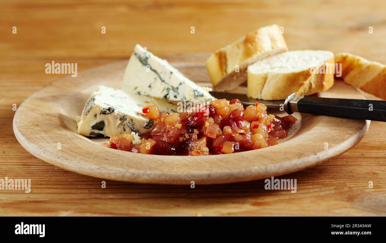 Süßer Birnen-Chutney mit Chili, serviert mit Blauschimmelkäse und Baguette in Scheiben auf einem Holzgericht Stockfoto