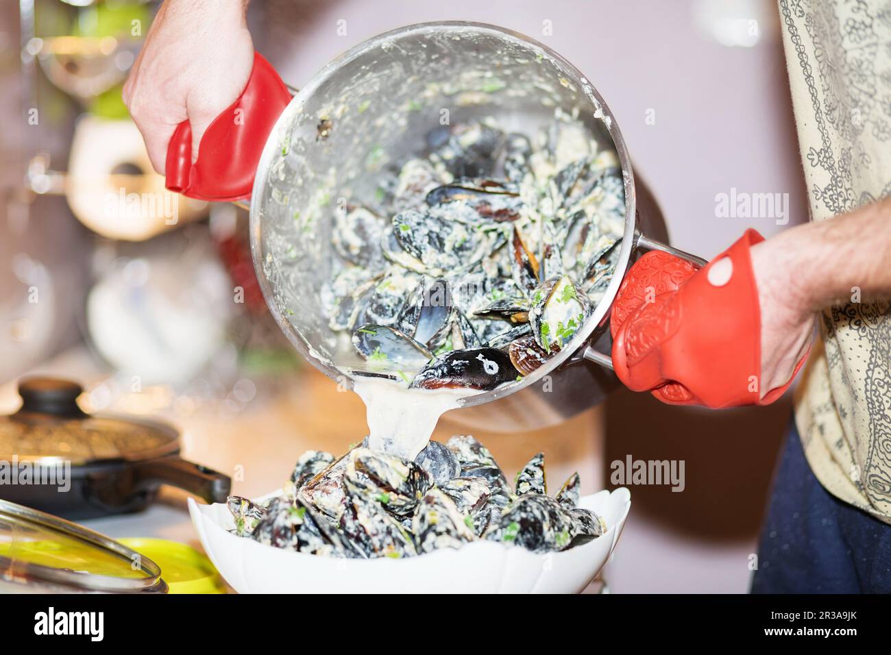 Gedämpfte Muscheln in Schalen in der Schüssel mit Weißwein auf dem Tisch. Der Chef kocht Muscheln in Käse Stockfoto