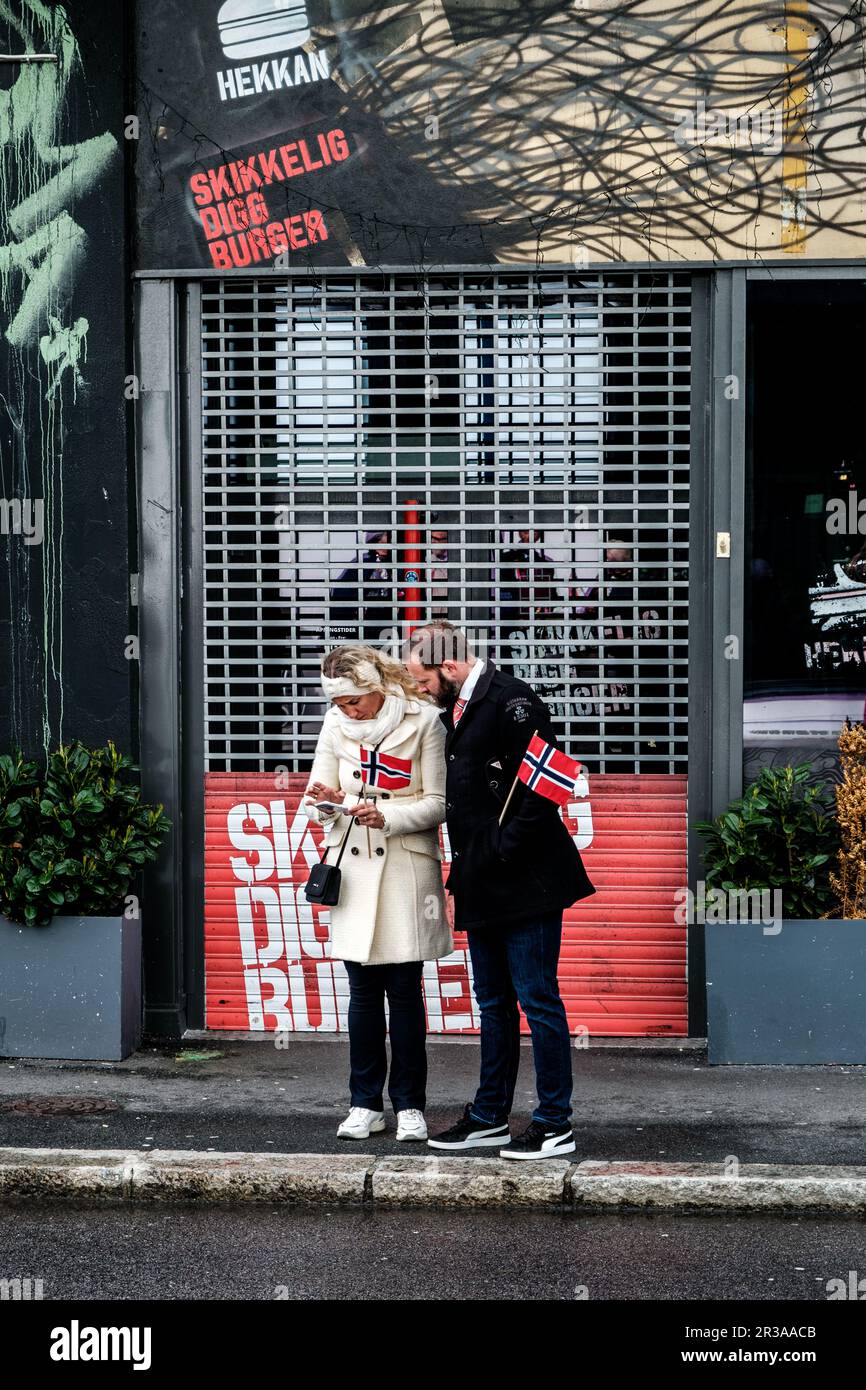 Sandnes, Norwegen, 17 2023. Mai, Mann-Frau-Paar steht an der Straßenecke und hält norwegische Flaggen-Verfassungstag Stockfoto