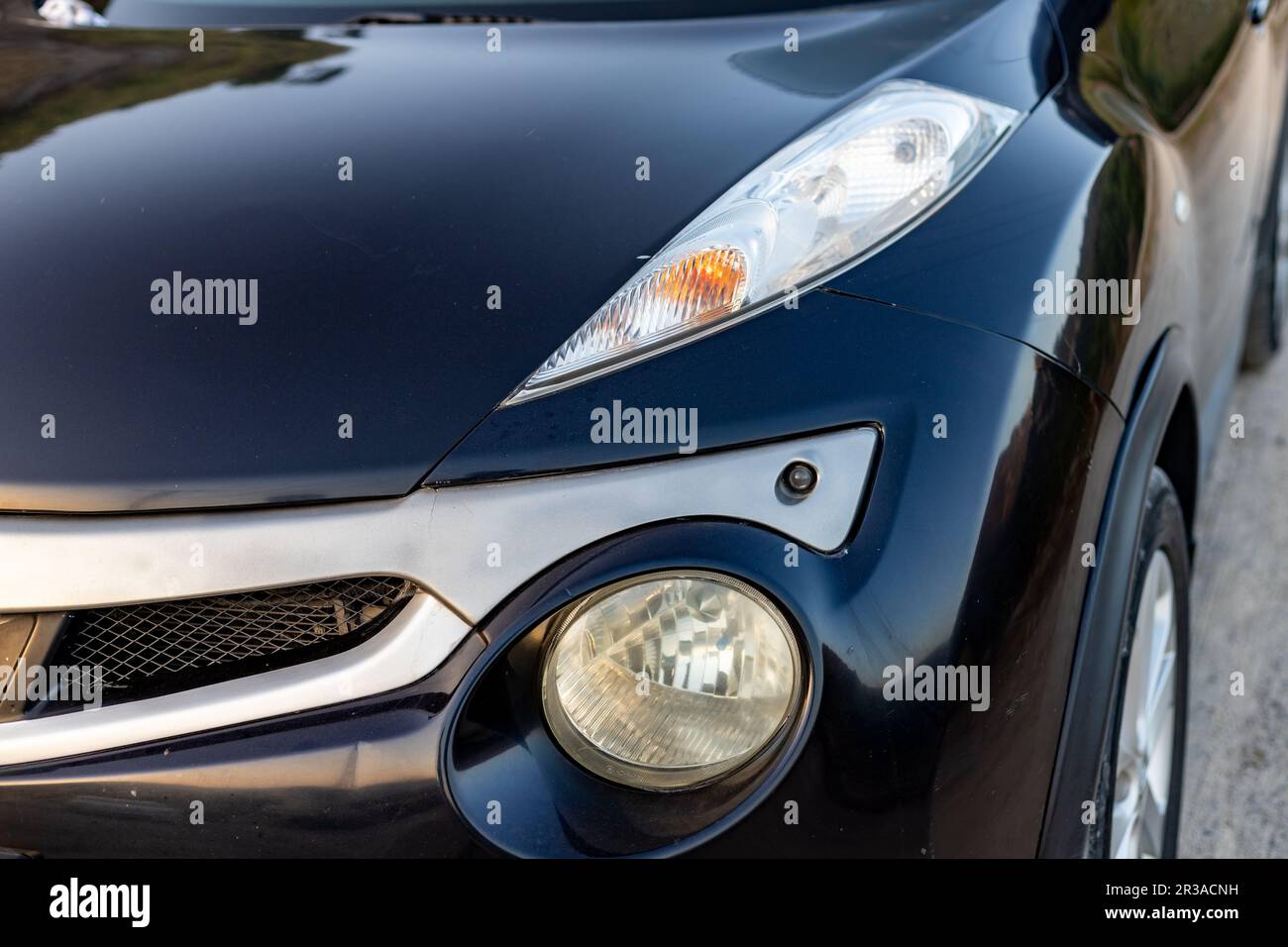 Nahaufnahme der impulsen Frontscheinwerfer und des Einparkhilfesensors von Nissan Juke Stockfoto